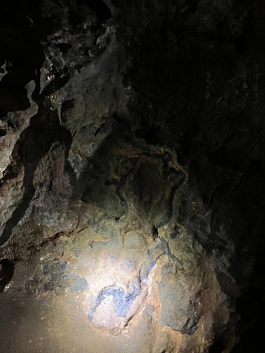 Dark rock face lit by a small beam of light.