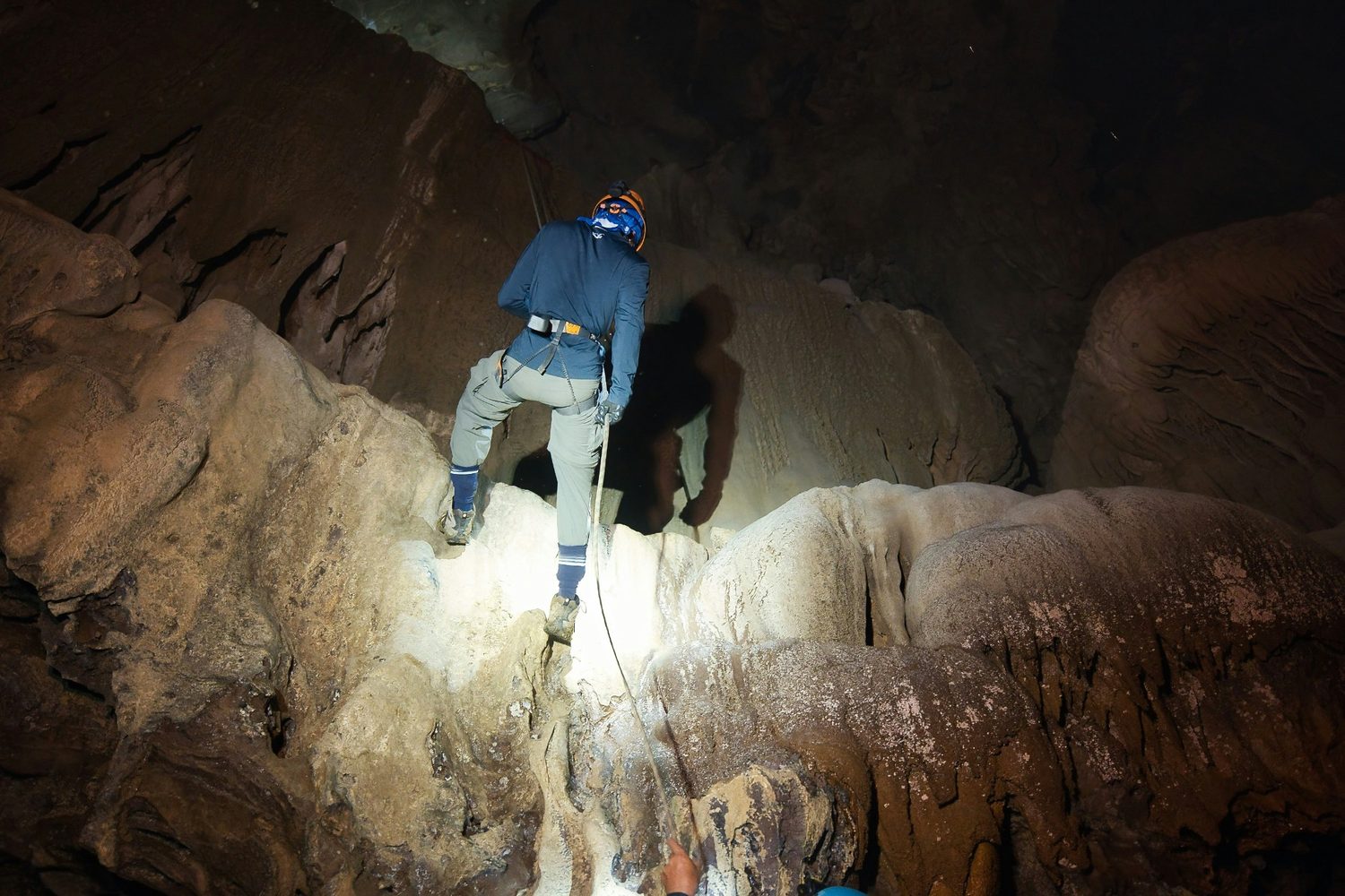 Explorer climbing through a rocky cavern.