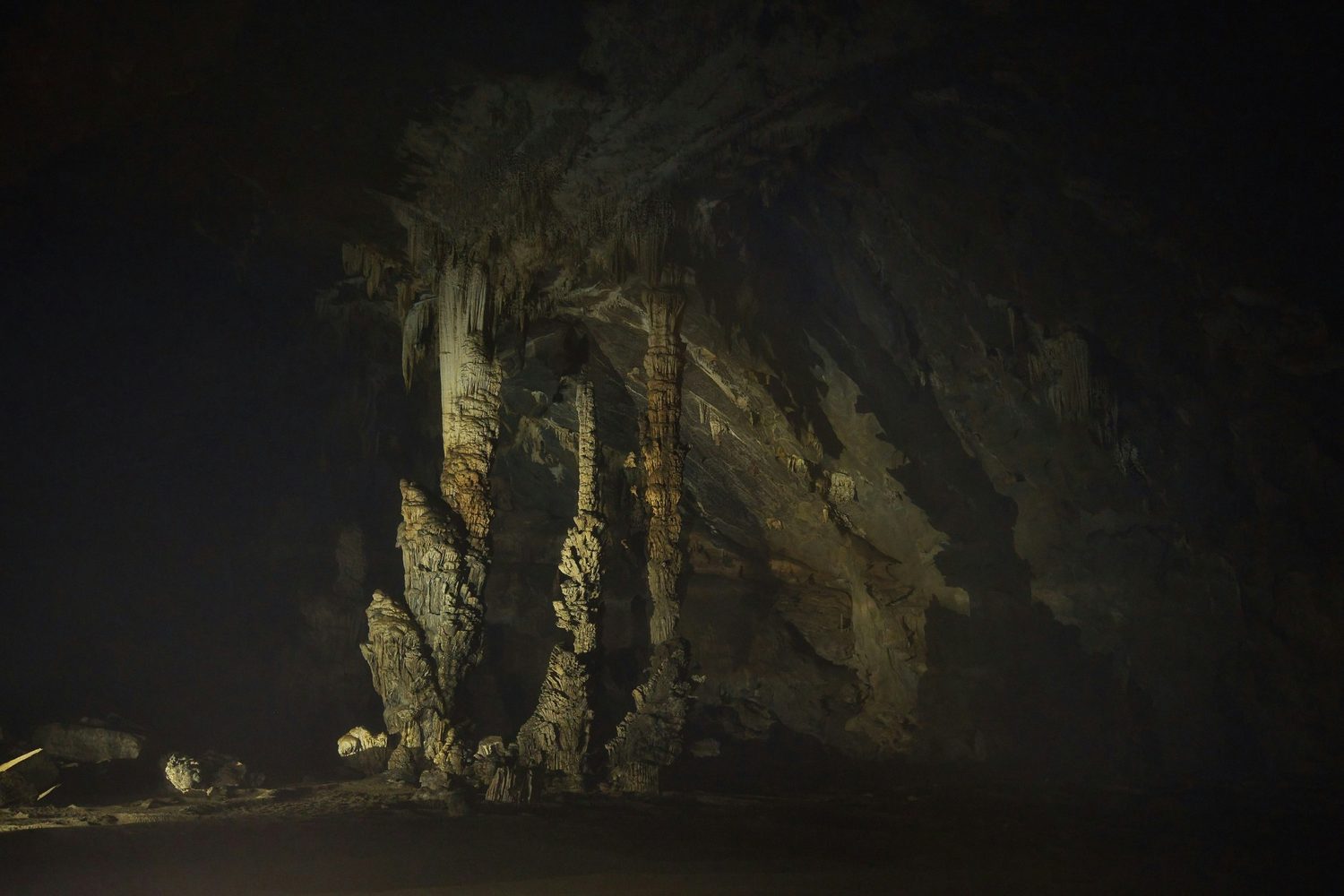 Stalagmites and rock formations in a dark cavern.