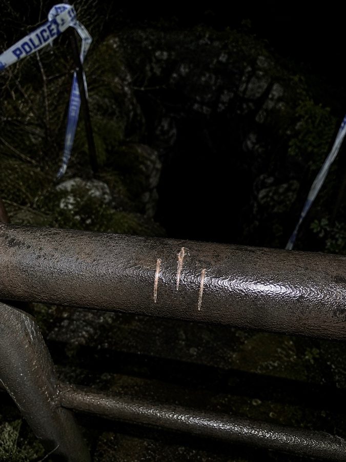 Small photograph of a scratched three-line symbol on a metal railing.
